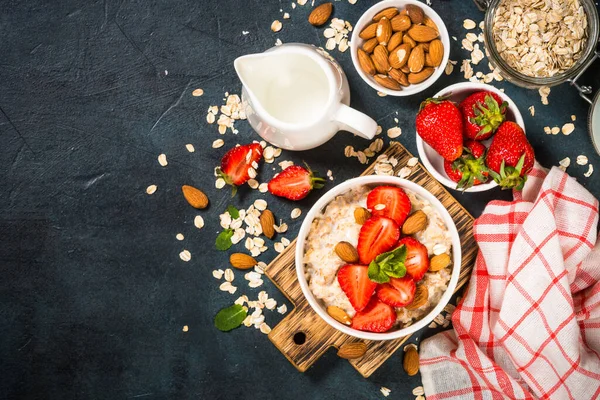 Havermout pap met verse aardbeien en noten op donkere achtergrond. — Stockfoto