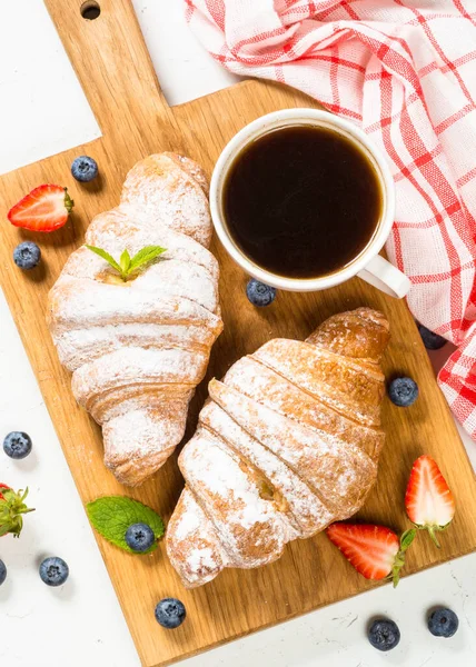 Croissant ze świeżymi jagodami i filiżanką kawy. — Zdjęcie stockowe