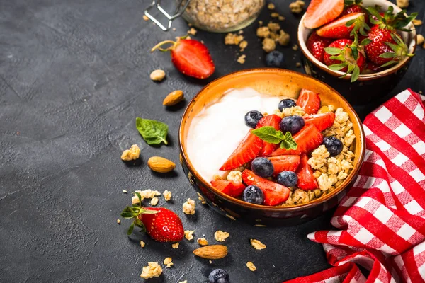 Granola yogurt Yunani dengan buah berry segar di atas meja batu hitam. — Stok Foto
