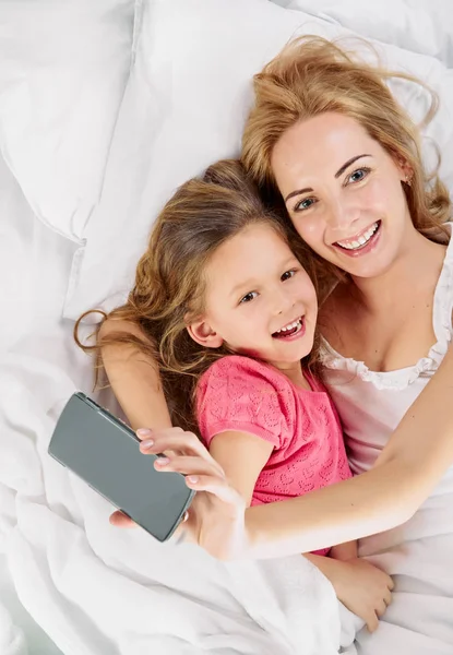 Madre hija. selfie en cama blanca —  Fotos de Stock