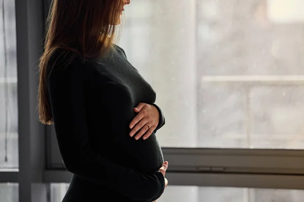 Красивая беременная женщина о окне — стоковое фото