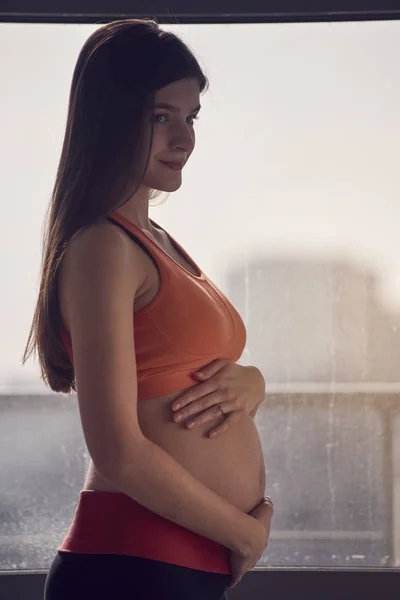 Беременная женщина о окне — стоковое фото