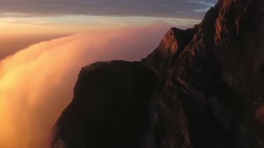 Günbatımı bulutları üzerinde Norveç dağı. En iyi bakış açısı. Bulutlardaki İHA 'dan hava görüntüsü. Helikopter harika bir uçurum manzarası çekti.