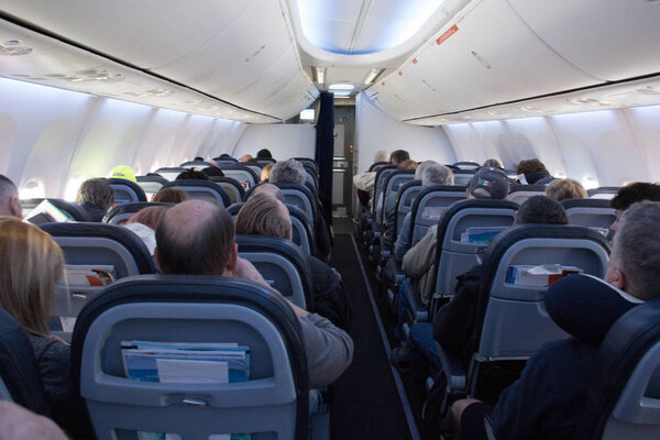 Looking down the aisle of economy class on a commercial passenger jet.