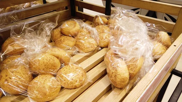 Supermarket bread department, breakfast rolls are lying on a wooden tray.