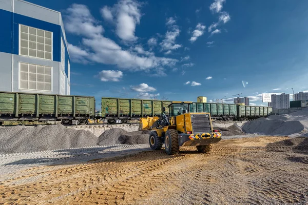 Wheel loader works in a warehouse of sand and gravel. Flyover for unloading railway freight cars.