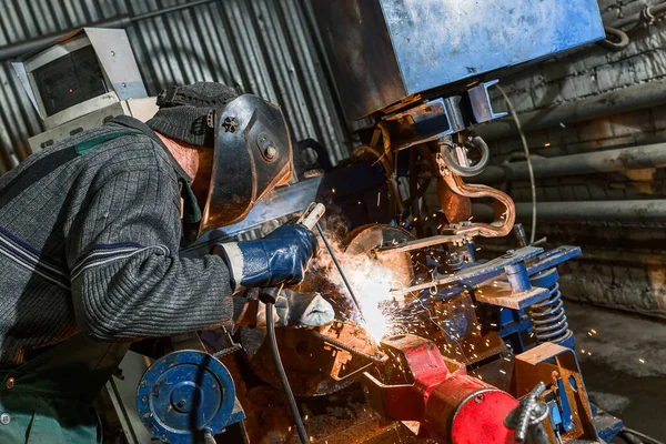 A welder is welding a steel billet for a pile.