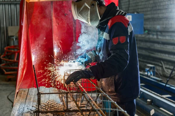 A welder is welding a steel billet for a pile.