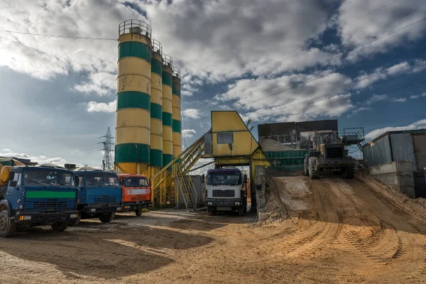 Concrete Plant. Several concrete truck vehicles are awaiting loading near cement storage towers.