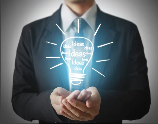 Business person holding light bulb — Stock Photo, Image