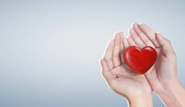 Mani con un cuore rosso, salute del cuore — Foto Stock