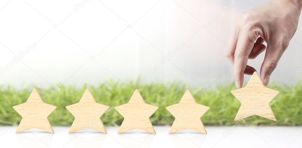 Wooden five star in hand shape. The best excellent business services rating customer experience concept