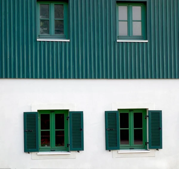 Fragment of windows with green shutters as an element of design.