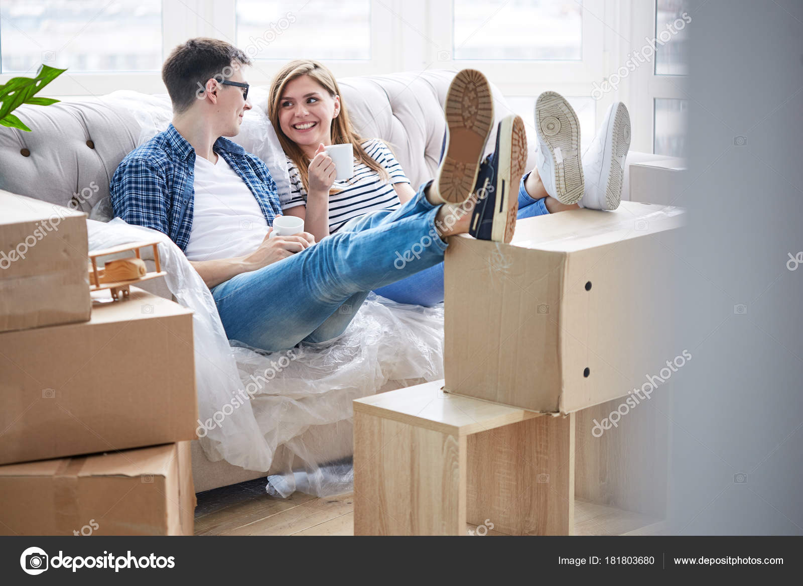 Joyful Young Couple Sitting Sofa Covered Plastic Wrap Enjoying