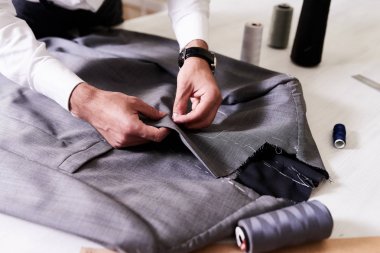 Üretim süreci ısmarlama erkek ceket: Tanınmayan terzi konsantre vurdu dikiş üzerinde iğne ve iplik, yakın çekim ile