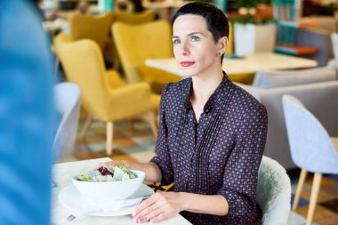 Onun önünde salata kasesi ile kafede masada oturan ve garson gülümseme ile bakarak memnun müşteri portresi