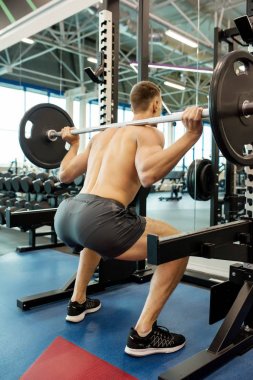 Modern spor salonunda egzersiz sırasında ağır halter ile halter egzersiz yapan güçlü bir adamın Arka görüş portresi