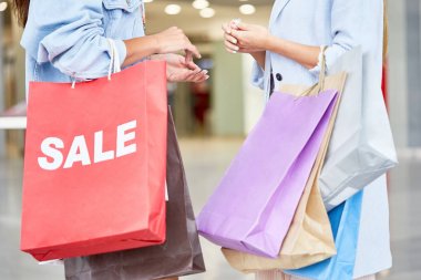 Orta bölüm portre alışveriş merkezinde Toplantı iki tanınmaz halde genç kadınların her ikisi de kağıt torba satın almalarla holding