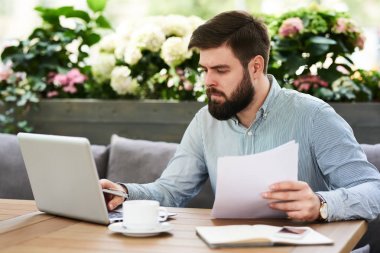 Rahat kafe salonda açık havada kahve molası sırasında çalışan genç sakallı işadamı portresi