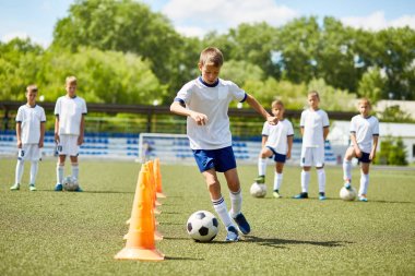 Boy kozalakları güneşli alanındaki uygulamaları sırasında arasında topu önde gelen genç futbol takımı içinde portresi