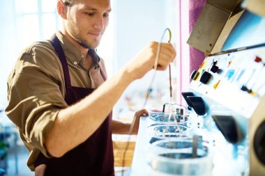 Metaller ile makine birimi tarafından kimyasal sıvı ayakta tedavi studio işçiliği çalışma gülümseyen genç adam portresi