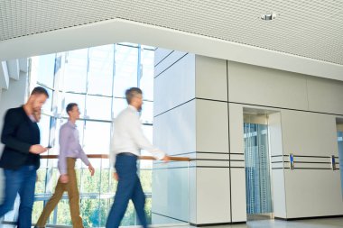Grup koridor modern ofis panoramik pencerelere, çekimde atış ile bina boyunca yürüyüş erkek meslektaşlarının