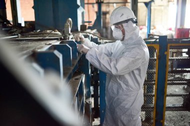 Yan görünümü biohazard takım elbise ve işçisi ayakta endüstriyel tesis açık atölyede giyen işçi portresi