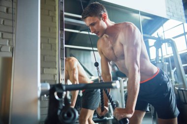 Spor salonu kullanarak çıplak göğüs eğitim ile yakışıklı kaslı adam portresi makine, egzersiz alanı kopyalayın