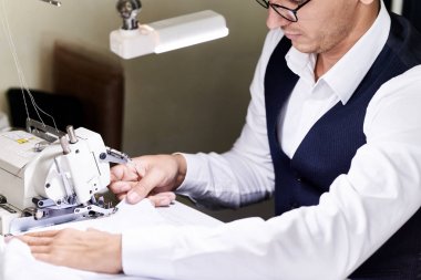 Yakışıklı terzi dikiş elbise Loş ışıkta Singer makinesiyle çalışan atelier masada portresi