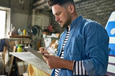 Yan görünüm portre yakışıklı sakallı adamın panoya atölye işçiliği çalışırken yazma