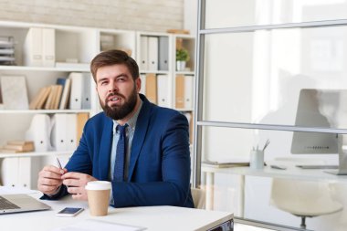 Uzak düşünceli modern ofis masasında çalışırken seyir başarılı sakallı işadamı portresi