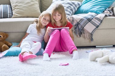 Katta oturan ve sevimli küçük kız kardeşi ise eğitim bilgisayar oyunu oynamak güzel kız başını omzuna dinlenme ve yaptıklarının ilgi ile takip