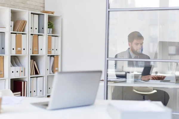 Background image of modern office space with desks and blurred businessman working behind glass wall, copy space