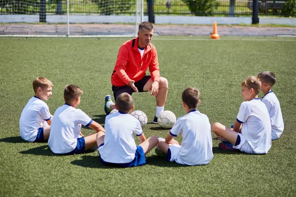 Retrato Del Equipo Chicos Sentado Frente Entrenador Campo Fútbol Escuchando — Foto de Stock