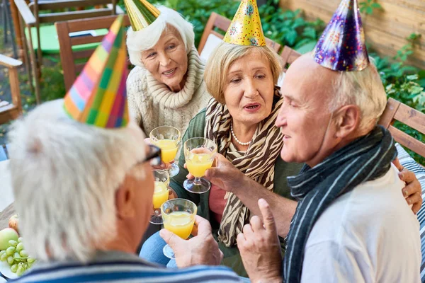 一群快乐的老年人穿着节日帽在户外露台与朋友庆祝生日 — 图库照片