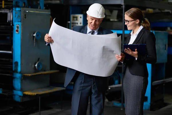 若いアシスタント マネージャーで近代的な工場の平面図を見て上級ビジネスマンの肖像画 — ストック写真