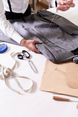 Son derece profesyonel genç çalışma ısmarlama erkek ceket iplik yardımıyla terzi ve masada, yakın çekim shot dururken iğne