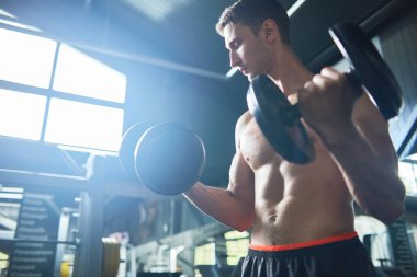 Çıplak göğüs modern spor salonunda çalışma dışarı ile seksi kaslı adam portresi motivasyonel düşük açılı