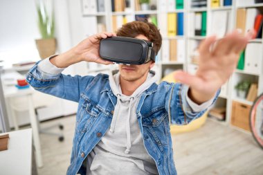 Genç adam silah ofis masasında oturan dışarı uzanan Vr bardaklarda video oyun oynarken portresi