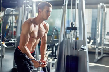 Çıplak kas gövde geniş spor olarak yoğun bir eğitim sırasında kablo crossover makinede egzersiz ile yakışıklı genç vücut geliştirmeci