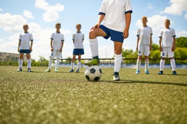 Arka planda takımın geri kalanı ile topu üzerinde adım alanının merkezinde duran futbol Kaptan düşük bölüm portresi