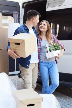 Mutlu genç çift Nakliye kamyonu apartmanın dışında için karton kutular yüklenirken kucaklayan portresi