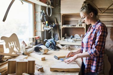 Ahşap tahta kalem ve dağınık atölye masada duran cetvel ile ölçme gözlük kendine güvenen genç craftswoman profil görünümü