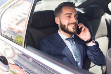 Arkada koltuk araba ve mutlu bir şekilde gülümseyerek oturan telefonla konuşan sakallı yakışıklı işadamı portresi