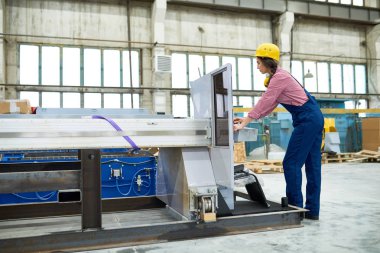 İşçi kask fabrika makine kullanırken program seçme yoğunlaştı