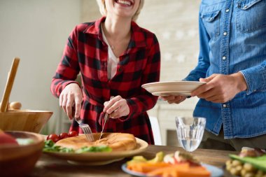 Yemek masasında duran ve tabakaları bana hizmet tanınmaz halde genç kadın kesme ev yapımı pasta orta bölümünde