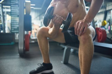 Tanınmayan vücut geliştirmeci geniş spor salonunda yoğun bir eğitim yaparken dumbbells ile kasların esneme