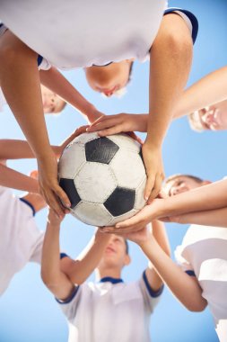 Erkek genç futbol takım topu bir arada karşı açık mavi gökyüzü tutan düşük açılı görünüş