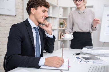 Yan görünüm portre yakışıklı modern ofis, masada oturan telefonla konuşan işadamı gülümseyen kopyalama alanı