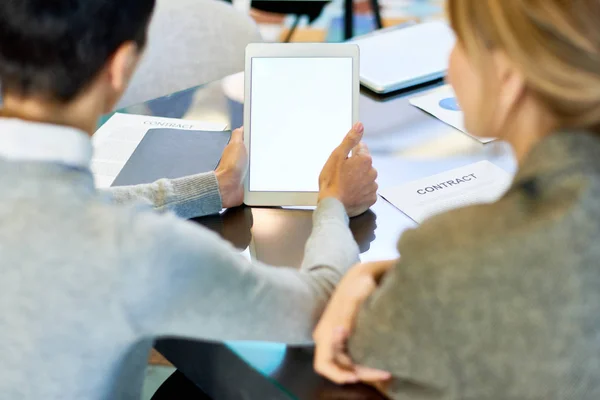 Back view portrait of two businesswoman using digital tablet during meeting, focus on white blank screen